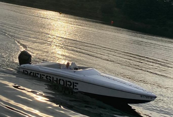 Frau auf einem Wakeboard hinter einem Boot