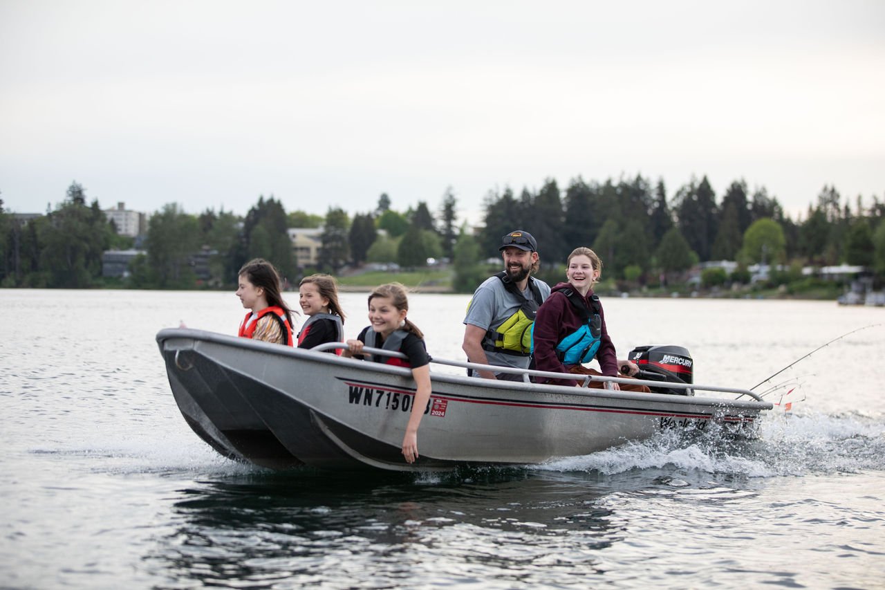 dad and kids in boat on water