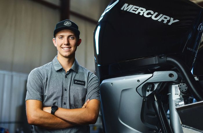 Man with folded arms next to a Mercury Marine outboard engine