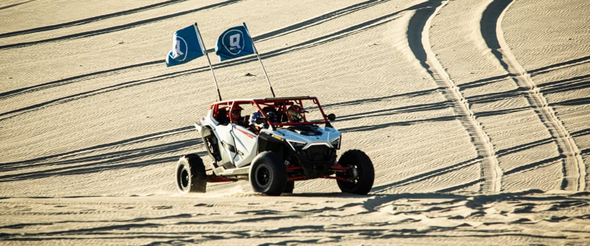 utv in desert with quicksilver flags