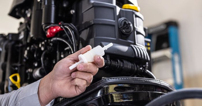 Hand holding a part next to an outboard engine